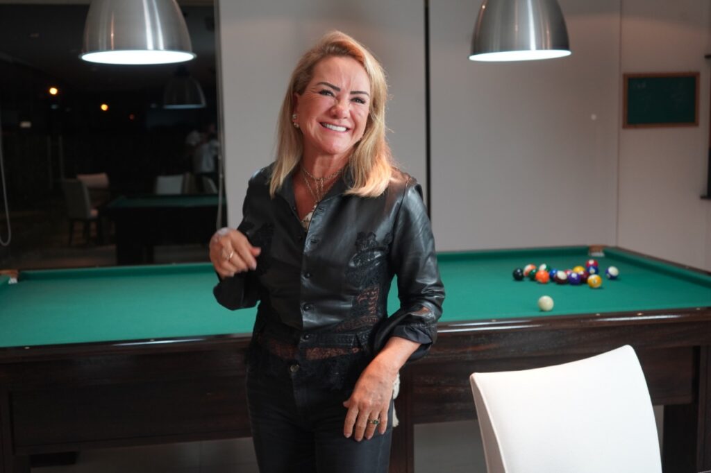 mulher loira com roupa preta em frente a uma mesa de sinuca