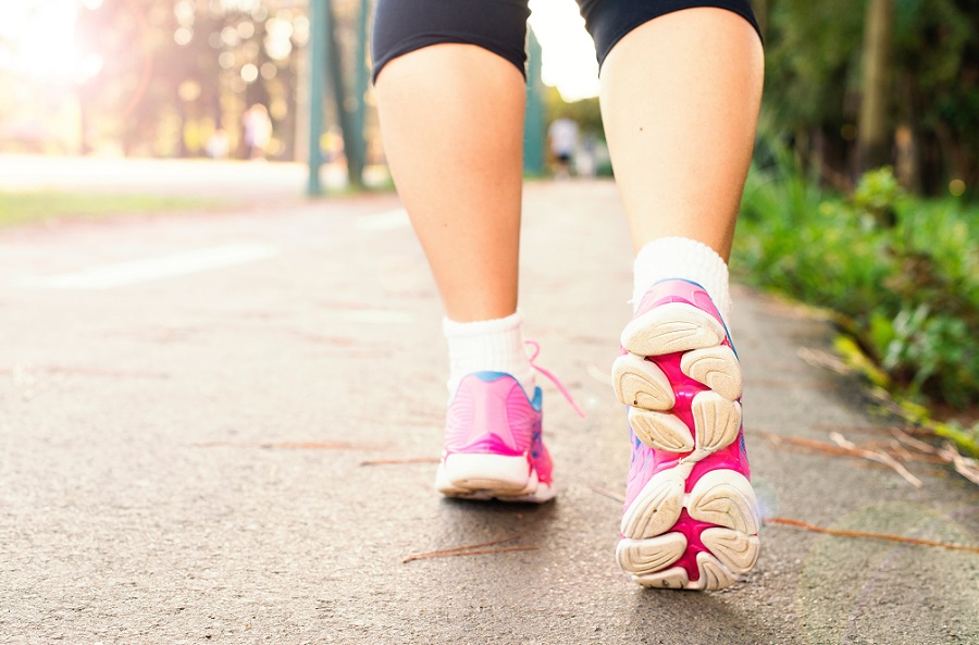 mulher caminhando no asfalto com tênis rosa