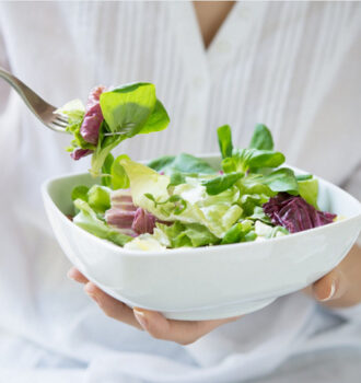 mulher segurando prato de salada verde