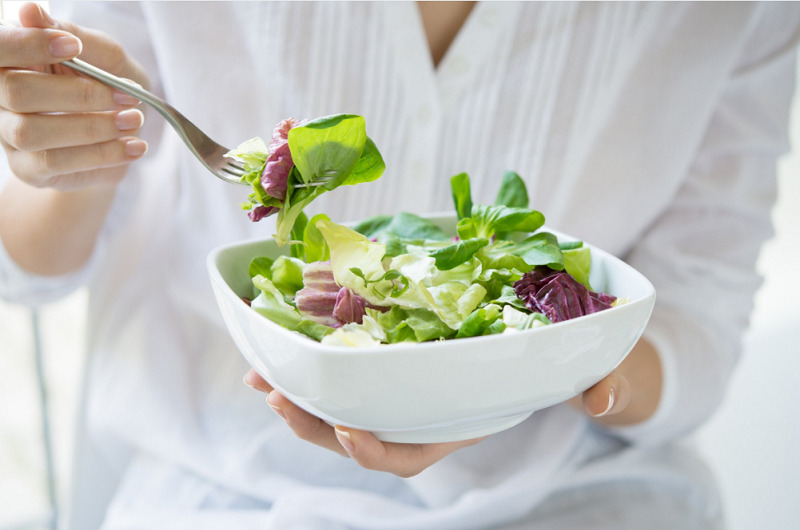 mulher segurando prato de salada verde